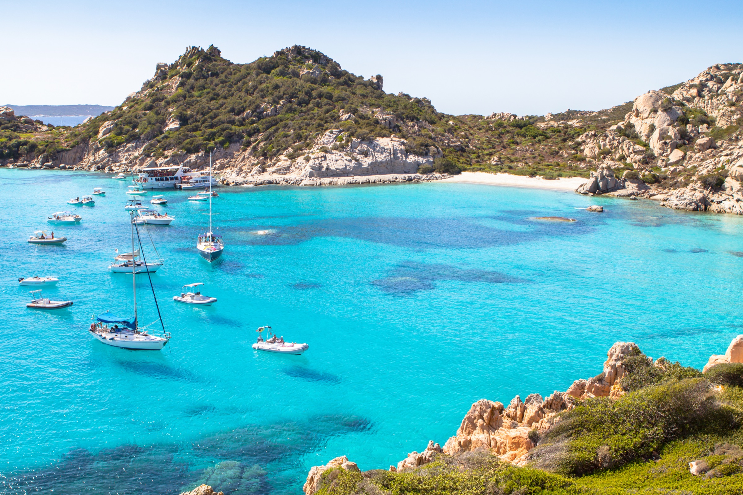 Sailboats anchored in a turquoise cove of the La Maddalena archipelago
