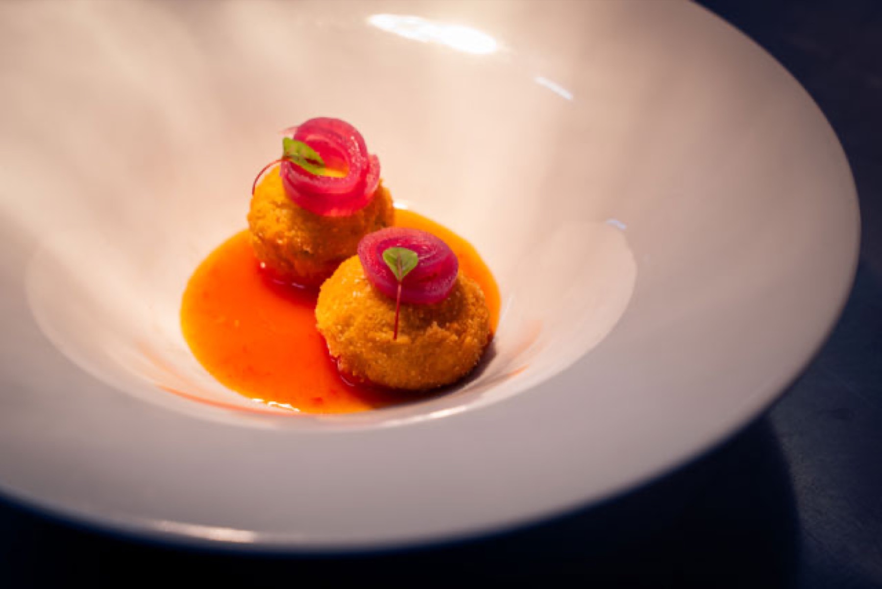 Two golden croquettes with red onion in a delicate sauce at Mesadoria