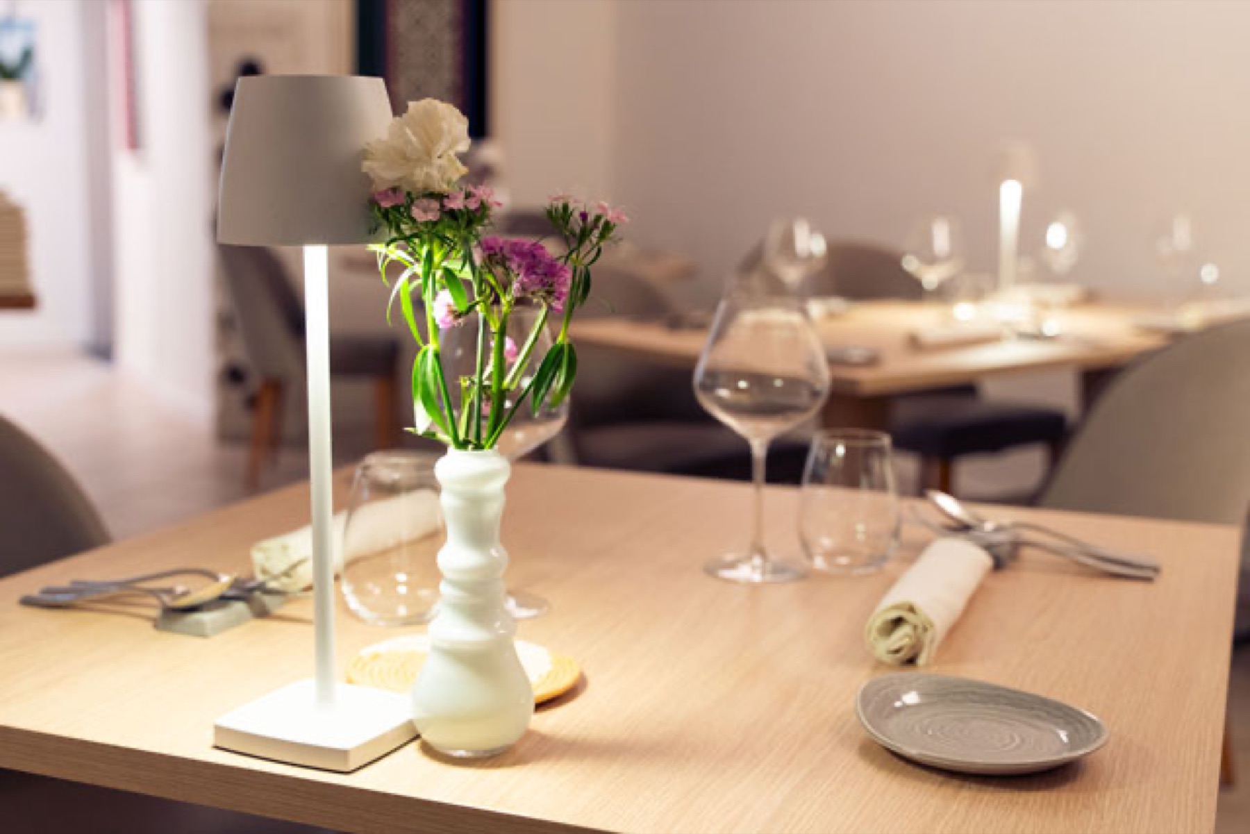 A set table at Mesadoria with a small vase of wildflowers and a soft modern dining room behind