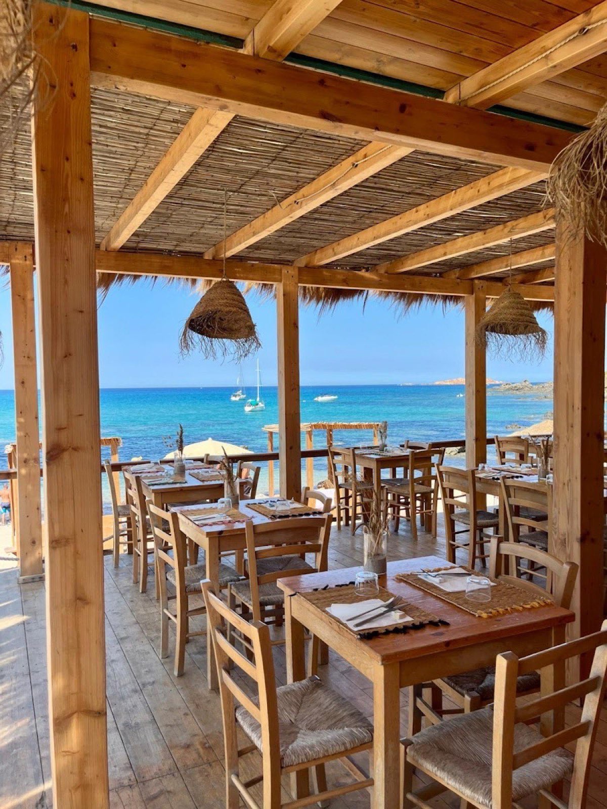 The wooden pergola dining deck at Santaluz Kiosko, looking out to the sea and a small boat