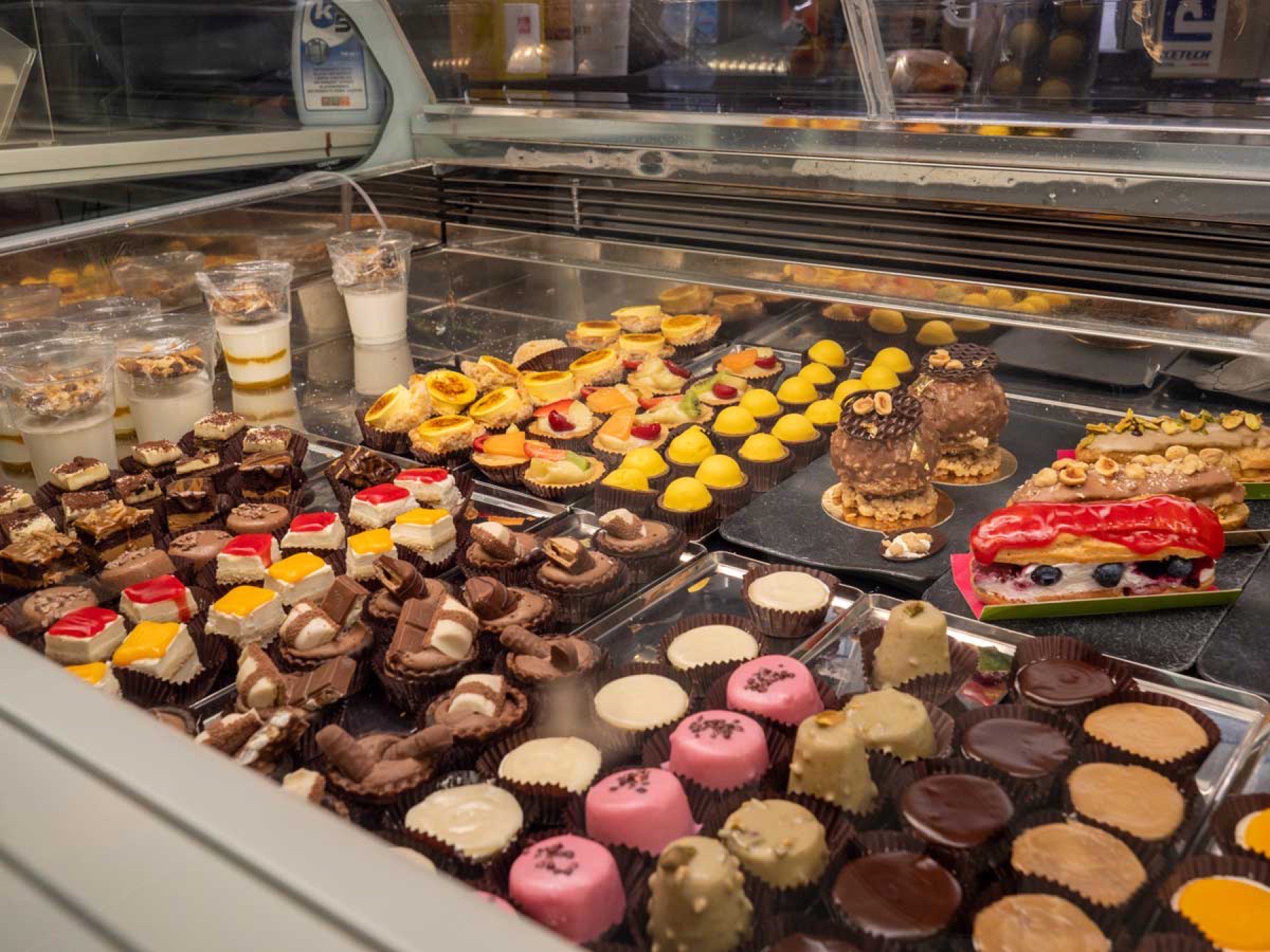 Pastry counter at Gelatomania, Badesi — mini cakes, eclairs, and Sardinian biscuits
